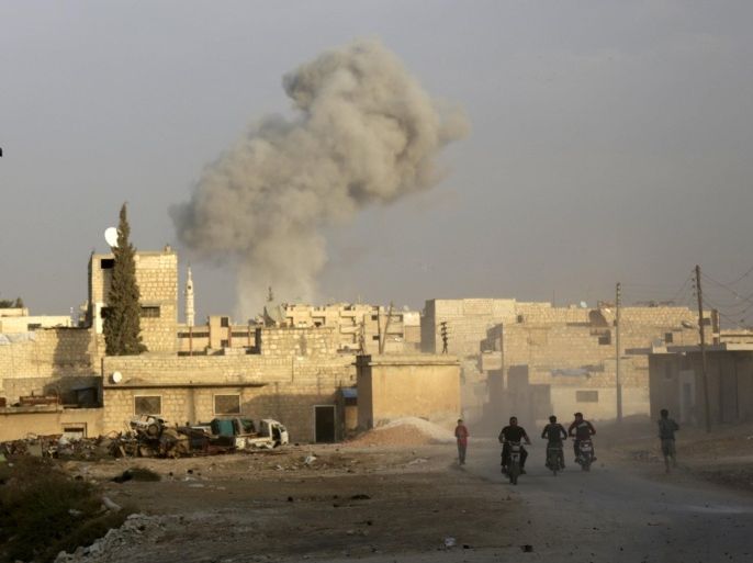 Residents ride motorcycles near smoke rising from what activists said was an airstrike carried out by the Russian air force in the rebel-controlled area of Maaret al-Numan town in Idlib province, Syria October 24, 2015. REUTERS/Khalil AshawiFOR EDITORIAL USE ONLY. NO RESALES. NO ARCHIVE.