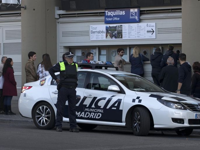 A police officer stands by a patrol car outside the Santiago Bernabeu stadium in Madrid, Spain, Thursday, Nov. 19, 2015. Spanish officials are promising unprecedented security measures for Saturday's soccer match between Real Madrid and Barcelona following the attacks in Paris. (AP Photo/Paul White)