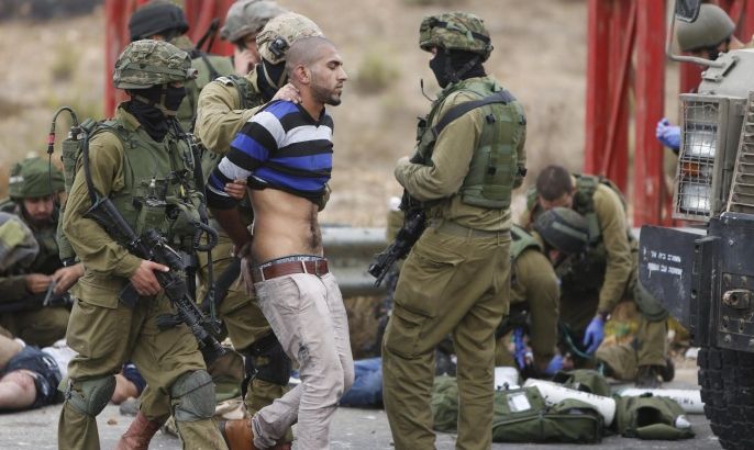 FILE - In this Wednesday, Oct. 7, 2015 file photo, Israeli soldiers arrest a man while others treat Palestinians wounded during clashes with the Israeli military, near Ramallah, West Bank. (AP Photo/Majdi Mohammed, File)