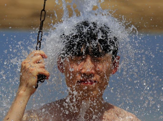 A boy takes a shower after bathing in the Dead Sea, near the West Bank city of Jericho, Sunday, Aug. 16, 2015. The region experienced another heat wave with temperatures in reaching well over 40 degrees Celsius (104 Fahrenheit) in some areas. (AP Photo/Hatem Moussa)