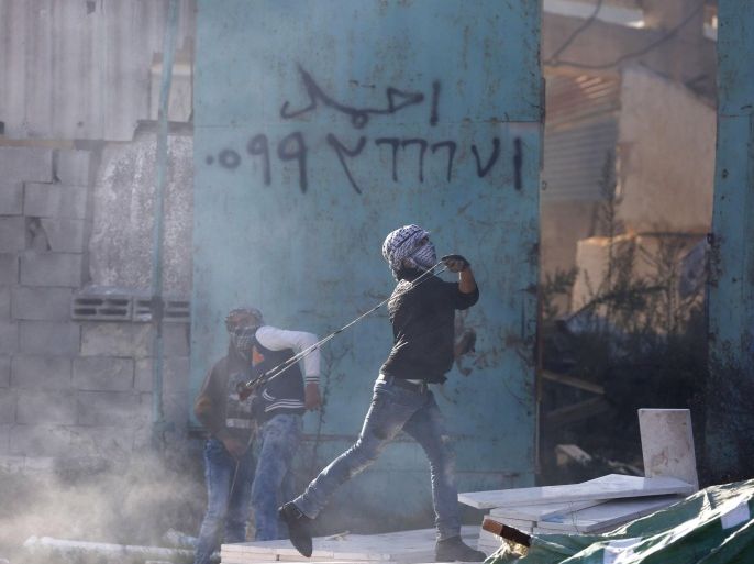 A Palestinian protester uses a slingshot to hurl stones during clashes with Israeli soldiers in the West Bank city of Hebron, Friday, Nov. 20, 2015. (AP Photo/ Nasser Shiyoukhi)