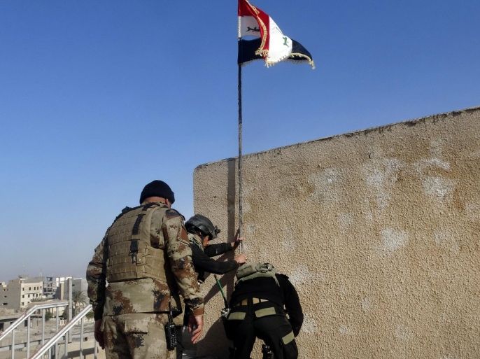 Iraqi soldiers plant a national flag in the government complex in central Ramadi, 70 miles (115 kilometers) west of Baghdad, Iraq, Monday, Dec. 28, 2015. Iraqi military forces on Monday retook a strategic government complex in the city of Ramadi from Islamic State militants who have occupied the city since May. (AP Photo)