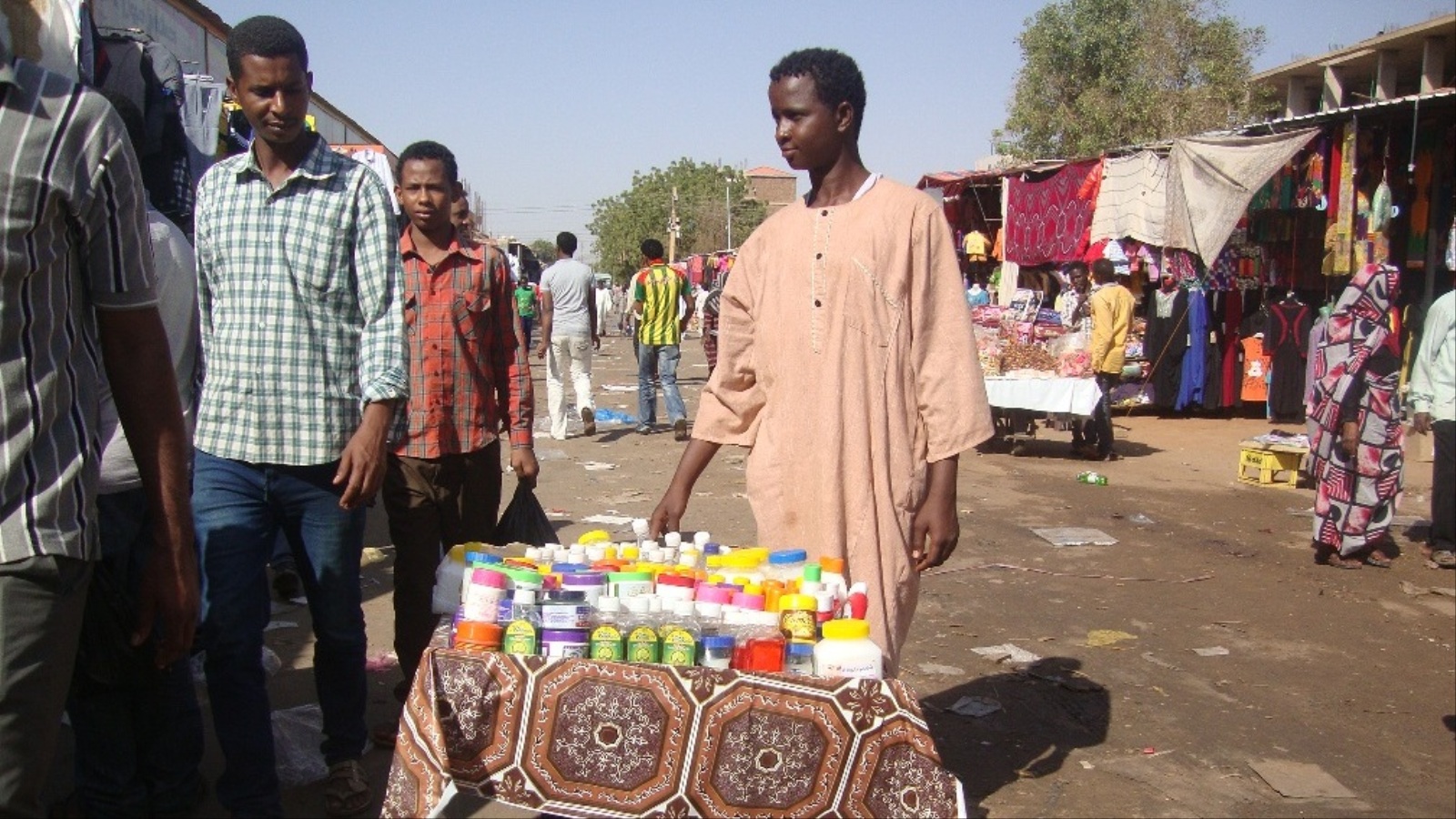 ‪الطالب السوداني مهند محمد يبيع سلعته على درداقة بأحد أسواق الخرطوم‬ (الجزيرة)