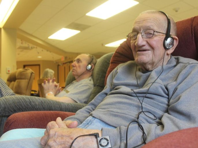 In this photo taken Sept. 4, 2014, in Union Grove, Wis., Mike Knutson, 96, smiles as he listens to music on an iPod. He is part of a study through the University of Wisconsin-Milwaukee that is looking at whether mood and behavior is altered when dementia and Alzheimer's patients listen to a personalized set of music. (AP Photo/Carrie Antlfinger)