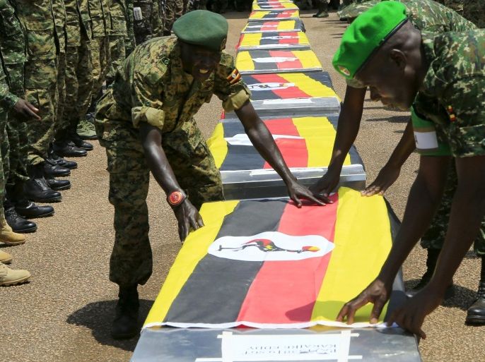 Uganda army soldiers lay national flags on the caskets carrying the remains of Ugandan soldiers who were killed in Somalia this week, at a military airbase in Entebbe September 3, 2015. Twelve Ugandan soldiers who served as African Union peacekeepers were killed when militants attacked their base in Somalia this week, a Ugandan military spokesman said on Thursday. REUTERS/James Akena