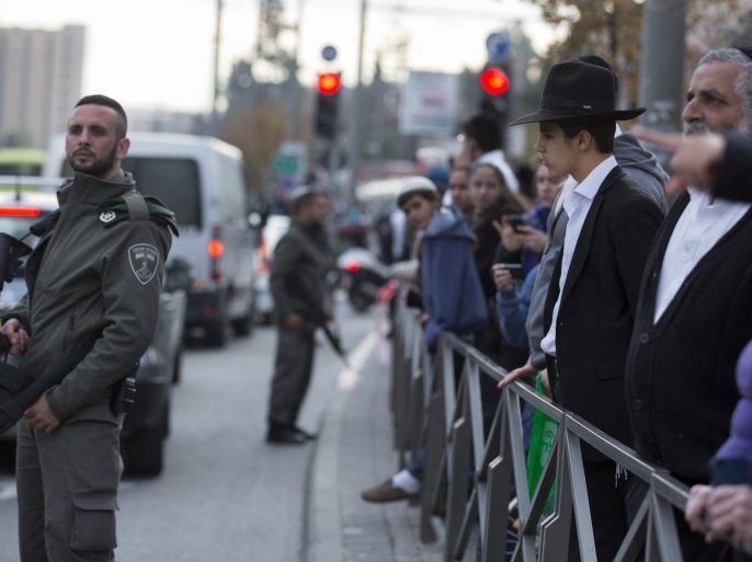 An ultra-Orthodox young man looks at the scene of a Palestinian attack that left 11 Israelis wounded at the entrance to Jerusalem, Israel, 14 December 2015, as Israeli Border Police keep pedestrians on the sidewalk. A Palestinian man rammed his car into a group of people at a bus stop, and then got out and began a stabbing attack until he was shot and killed by Israeli security forces. Among the wounded were a one-and-half year-old child and a 65-year-old woman.