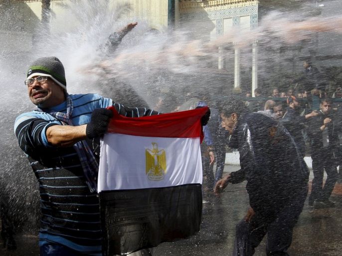 A protester holds an Egyptian flag as he stands in front of water cannons during clashes in Cairo January 28, 2011. Five years ago thousands of protesters took to the streets demanding the end of the 30-year reign of President Mubarak as Egypt became the second country to join the Arab Spring. After weeks of clashes, strikes and protests across Egypt, Mubarak resigned on February 11, 2011.   REUTERS/Yannis Behrakis   SEARCH "EGYPT UPRISING" FOR ALL IMAGES