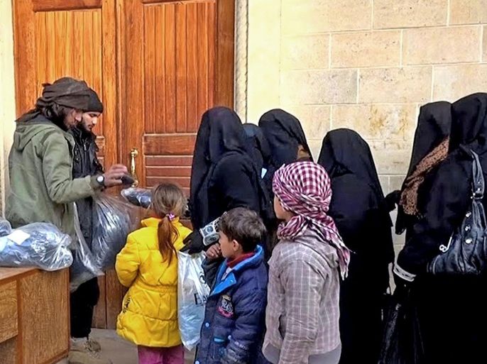 FILE - In this photo released on Jan. 31, 2014, by a militant website, which has been verified and is consistent with other AP reporting, members of the Islamic State group, left, distribute niqabs, enveloping black robes and veils that leave only the eyes visible, to Iraqi women in Mosul, northern Iraq. One perk of being an IS member is the chance to marry local women. Several Syrians interviewed by the AP said families with daughters often came under pressure to marry them off to fighters. (Militant website via AP, File)