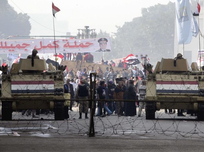 Egyptians soldiers posted at one of the entrance of Tahrir square as people supporting the army and its Defense Minister Abdel Fatah al-Sissi (pictured in banner in the background) gather to celebrate the anniversary of the 25th January 2011 revolution, at Tahrir square, Cairo, Egypt, 25 January 2014. Increased security was visible across Cairo as Egyptian officials prepared for rival political groups holding rallies to mark the third anniversary of the start of the 2011 uprising that forced out former president Hosni Mubarak. Security forces were deployed around major squares and outside key state installations, one day after a series of bomb attacks targeted police facilities in the Egyptian capital, killing six people and injuring more than 80.
