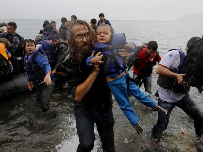 File photograph shows a volunteer carrying a Syrian refugee child off an overcrowded dinghy at a beach after the migrants crossed part of the Aegean Sea from Turkey to the Greek island of Lesbos September 23, 2015. Britain might take in refugee children who have been displaced by the war in Syria and have traveled to other countries in Europe, a government minister said on January 24, 2016. International Development Secretary Justine Greening said the government was considering whether it could do more for the estimated 3,000 children who have fled the conflict without their parents or guardians and are in Europe. REUTERS/Yannis Behrakis/files