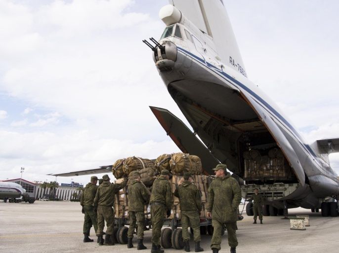 Russian air force personnel prepare to load humanitarian cargo on board a Syrian plane at Hemeimeem air base in Syria, Wednesday, Jan. 20, 2016. Russian warplanes fly dozens of combat sorties a day,pressing Moscow's air blitz ahead of the scheduled Syria peace talks in Geneva. (AP Photo/Vladimir Isachenkov)