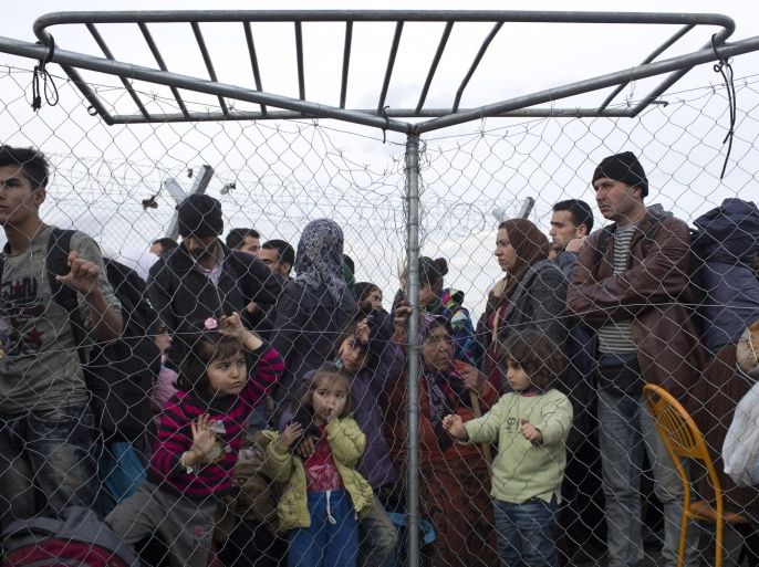 Refugees stand behind an iron fence  as they wait to be allowed to cross the border from the Greek side to the Macedonian one at the northern Greek border station of Idomeni, Saturday, Feb. 27, 2016. Around 300 people crossed to Macedonia so far today with more than 5,000 people waiting at or near a border crossing to be admitted. More than 20,000 migrants are stuck in Greece,  (AP Photo/Petros Giannakouris)