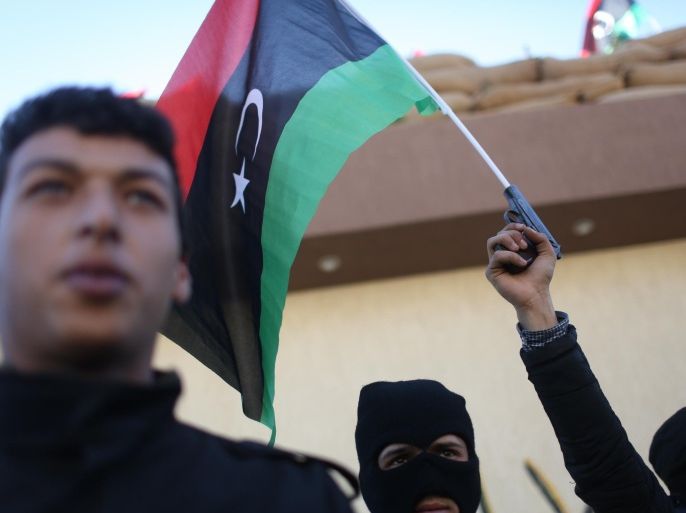 Libyan security forces stand in front of the security headquarters, one showing his weapon with a Libyan flag, in the western city of Sabratha, Libya, Saturday, Feb. 20, 2016. American fighter-bombers struck an Islamic State militant training camp in rural Libya near Sabratha Friday, killing dozens. Serbian officials say two Serbian embassy staffers who had been held hostage since November are believed to have been killed in the airstrikes. Washington and its European allies are seeking to end the interminable divisions among Libyan factions to form a unity government that the West can support in fighting the jihadis. (AP Photo/Mohamed Ben Khalifa)