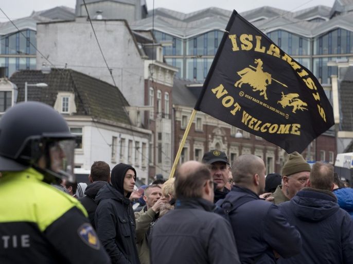 Riots police separates pro and anti immigration demonstrators as a man waves a flag reading "Islamists Not Welcome" during a Pegida demonstration in Amsterdam, Netherlands, Saturday, Feb. 6, 2016. Thousands of people took part in protests against Islam and immigration in several European cities. (AP Photo/Peter Dejong)