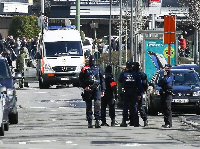 Belgian police stand in distance as a bomb disposal expert in heavy protection gear (L, background) arrives at the scene of an apparent operation against terror suspects near the Meizer round about in the Schaerbeek district of Brussels, Belgium, 25 March 2016. Media reported the sound of gunfire and explosions during the raid which is believed to be linked to the investigation into the 22 March Brussels terrorist attacks which caused the death of at least 31 people and injured hundreds of others and for which the so-call 'Islamic State' (IS) had claimed responsibility. According to Belgian RTBF broadcasting company one person was arrested in the operation.