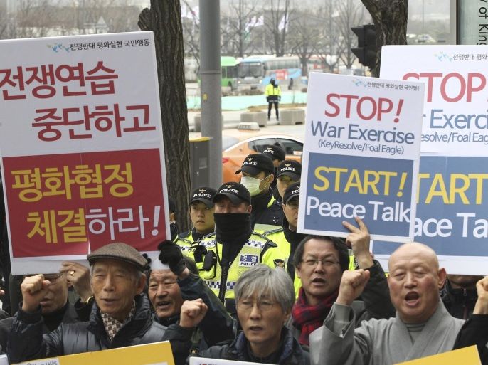 Anti-war protesters shout slogans during a rally opposing the joint military exercises, dubbed Key Resolve and Foal Eagle, between the U.S. and South Korea as police officers stand guard near the U.S. Embassy in Seoul, South Korea, Monday, March 7, 2016. North Korea on Monday issued its latest belligerent threat, warning of an indiscriminate "pre-emptive nuclear strike of justice" on Washington and Seoul, this time in reaction to the start of huge U.S.-South Korean military drills. The signs at left read: "Stop, the joint military exercises between the U.S. and South Korea." (AP Photo/Ahn Young-joon)