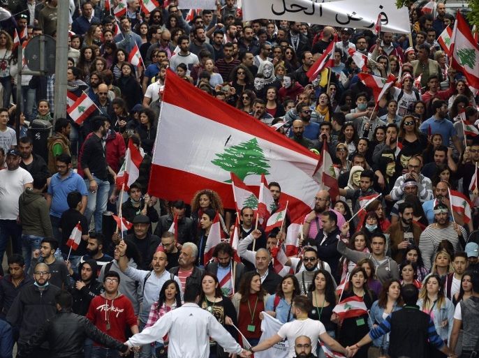 Lebanese activists from the 'You Stink' movement and other civil democratic movements wave their national flag and carry placards as they walk during a protest against the ongoing garbage crisis in front of the Lebanese government palace, downtown Beirut, Lebanon, 12 March 2016. The protesters demanded solutions for the ongoing garbage crisis, and abolition of corruption and accounting the corrupt.