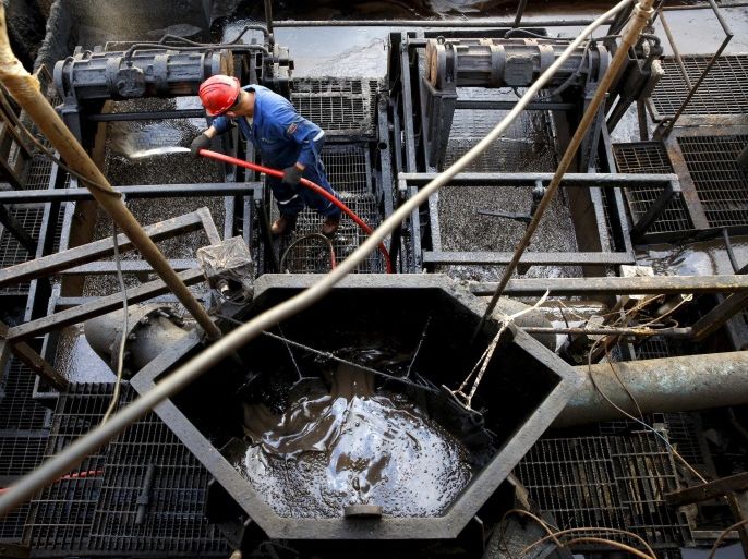 The flow of crude oil is seen in a container while an oilfield worker works on a drilling rig at an oil well operated by Venezuela's state oil company PDVSA, near Cabrutica, Venezuela in this April 16, 2015 file photo. REUTERS/Carlos Garcia Rawlins/Files