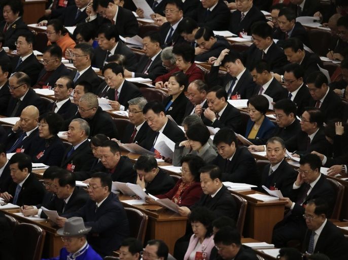 In this Saturday, March 5, 2016 photo, delegates read the work report during the opening session of the National People's Congress (NPC) at the Great Hall of the People in Beijing. Unlike legislatures elsewhere, China’s does little in the way of legislating, is carefully stage-managed and allows no foreign leader to address it. But like such chambers of power elsewhere, China’s has become something of a billionaire’s club, where the super-rich sit shoulder-to-shoulder with colorfully adorned Tibetan, Mongolian and other minority delegates and members of the country’s vast bureaucracy. (AP Photo/Andy Wong)