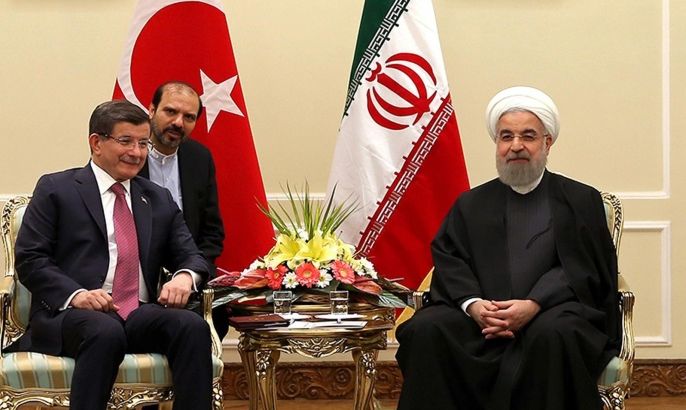 In this photo released by an official website of the office of the Iranian Presidency, President Hassan Rouhani, right, meets with Turkish Prime Minister Ahmet Davutoglu under portraits of the late Iranian revolutionary founder Ayatollah Khomeini, left, and Supreme Leader Ayatollah Ali Khamenei, at his office in Tehran, Iran, Saturday, March 5, 2016. An unidentified interpreter sits in background. (Iranian Presidency Office via AP)