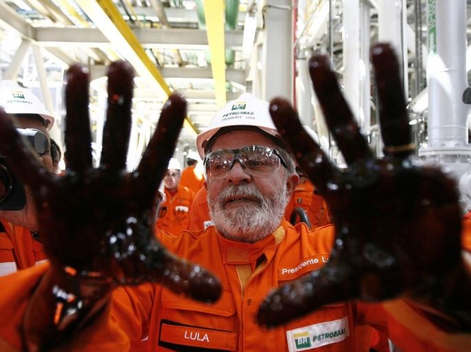 (FILE) A file photo dated 28 October 2010 of then Brazilian President Luiz Inacio Lula da Silva posing with his hands full of oil as he takes part in the launch of the Petrobras platform 'Ciudad de Angra dos Reis' on the Brazilian coast on the Atlantic. Media reports on 04 March 2016 state that Lula's home was raided within the investigations into a corruption scandal of Brazil's state-run oil company Petrobras. Brazilian authotrities already in September 2015 were seeking to question former president Luiz Inacio Lula da Silva, on suspicion that he may have benefited from corruption at the state-owned oil company. EPA/MARCELO SAYAO *** Local Caption *** 02417576
