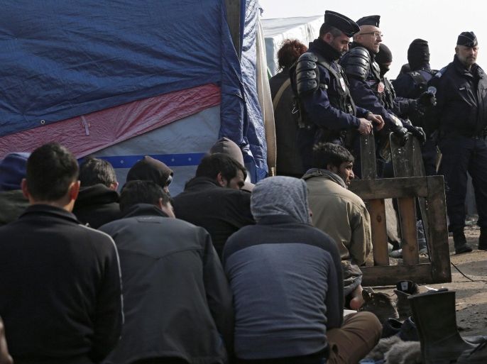 Migrants pray under police surveillance during the dismantling of the makeshift shelter migrant camp dubbed the 'Jungle' in Calais, France, 11 March 2016. French authorities have begun clearing part of Calais' sprawling migrant camp, whose population surged to over 6,000 last year, in a bid to encourage migrants to seek asylum in France.