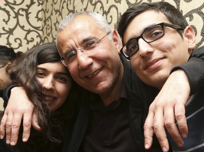 Human rights activist Intigam Aliyev, center, poses for a photo with his son and daughter upon his release at home in Baku, Azerbaijan, Monday, March 28, 2016. A court in Azerbaijan has ordered the release of a human rights activist who spent the last two years in jail. Aliyev was convicted last year of economic crimes that critics have dismissed as retaliation for his work. (AP Photo/Aziz Karimov)