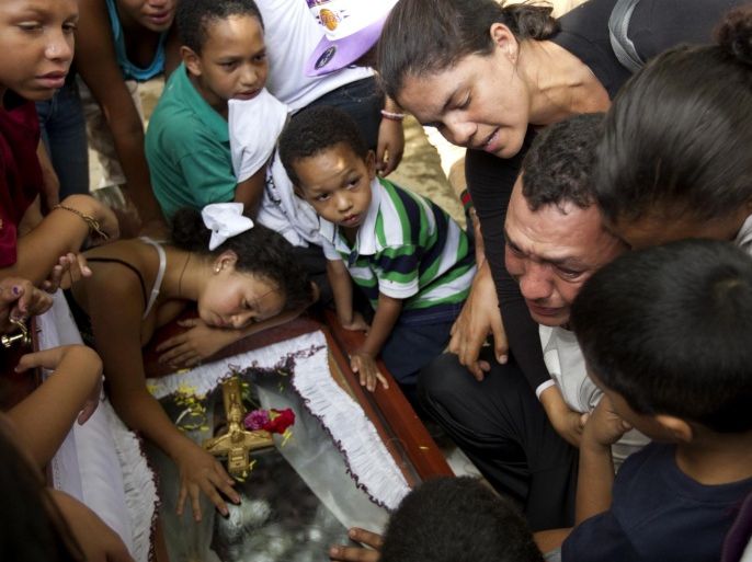 Relatives of a gunshot victim cry over his coffin during his funeral ceremony in Caracas November 27, 2012. A perpetually edgy city, Caracas' murder rate has shot up in recent years to become one of the world's worst. Both Venezuela's official national rate of 39 deaths a year per 100,000 people and an NGO tally of double that make the country an international leader in homicides, vying with gang-plagued nations such as Honduras and El Salvador. Some 100 undertakers' businesses, legal and illegal, have sprung up around Caracas in recent years. Nor is there a lack of demand for tomb-chisellers, flower-sellers, permit-handlers and a plethora of other mini-businesses purveying to death. Picture taken November 27, 2012. REUTERS/Carlos Garcia Rawlins (VENEZUELA - Tags: CIVIL UNREST CRIME LAW POLITICS TPX IMAGES OF THE DAY)ATTENTION EDITORS: PICTURE 26 OF 34 FOR PACKAGE 'IN CARACAS - THE BUSINESS OF DEATH'. TO FIND ALL IMAGES SEARCH 'DEATH CARLOS'