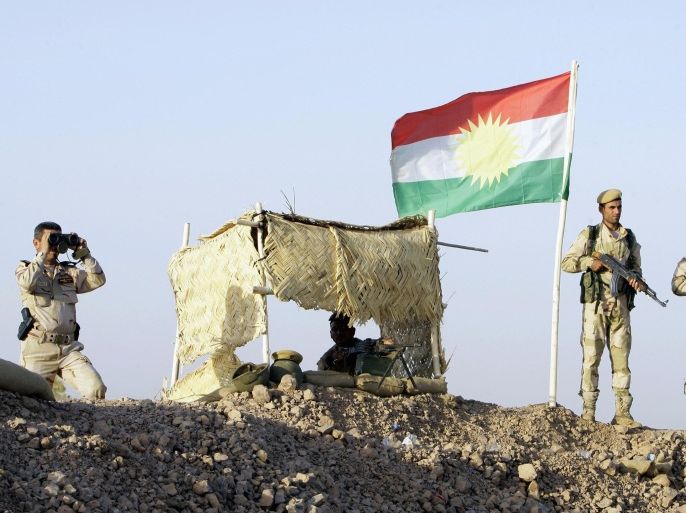 Kurdish Peshmerga soldiers look on at a guard post during a deployment in the area near the northern Iraqi border with Syria, which lies in an area disputed by Baghdad and the Kurdish region of Ninawa province, August 6, 2012. Beneath the green, white and red Kurdistan flag, Kurdish Peshmerga troops keep watch from hastily built earthen barricades on soldiers of the Iraqi national army dug in less than a kilometer away along a desolate stretch of road. Picture taken August 6, 2012. To match Analysis SYRIA-CRISIS/IRAQ-KURDISTAN/ REUTERS/Azad Lashkari (IRAQ - Tags: CONFLICT POLITICS MILITARY)