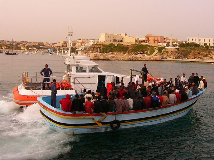 قارب يحمل لاجئين أريتريين وصوماليين فادمين من ليبيا عند دخوله جزيرة لامبيدوزا برفقة خفر السواحل الإيطالي .الجزيرة