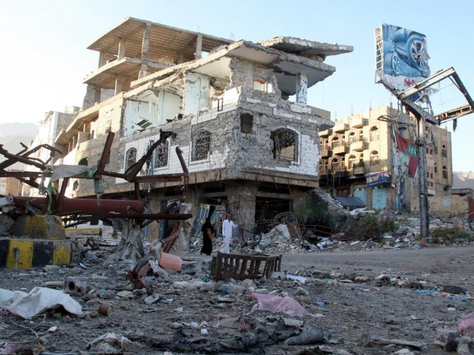 People walk past a building destroyed during recent fighting in Yemen's southwestern city of Taiz March 14, 2016. REUTERS/Anees Mahyoub
