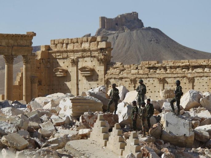 Syrian army soldiers stands on the ruins of the Temple of Bel in the historic city of Palmyra, in Homs Governorate, Syria April 1, 2016. The Fakhreddin's Castle is seen in the background. REUTERS/Omar Sanadiki