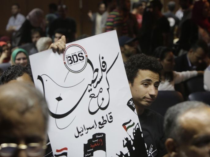 An Egyptian raises a poster with the Boycott, Divestment and Sanctions (BDS) logo and Arabic that reads, "we are all with Palestine, boycott Israel," during the launch of the Egyptian campaign that urges boycott, divestment and sanctions against Israel and Israeli-made goods, at the Egyptian Journalists’ Syndicate in Cairo, Egypt, Monday, April 20, 2015. BDS is a global movement initiated by Palestinian civil society activists in 2005 that organizers say will continue until Israel complies with international law and respects Palestinian rights. (AP Photo/Amr Nabil)