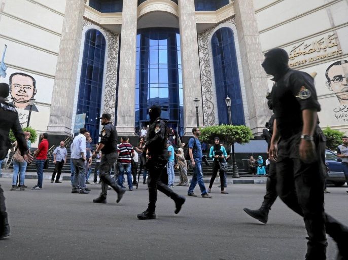 Masked Egyptian security forces walk by a demonstration held by journalists and activists against the detention of journalists, in front of the Press Syndicate in Cairo, Egypt April 26, 2016. REUTERS/Mohamed Abd El Ghany