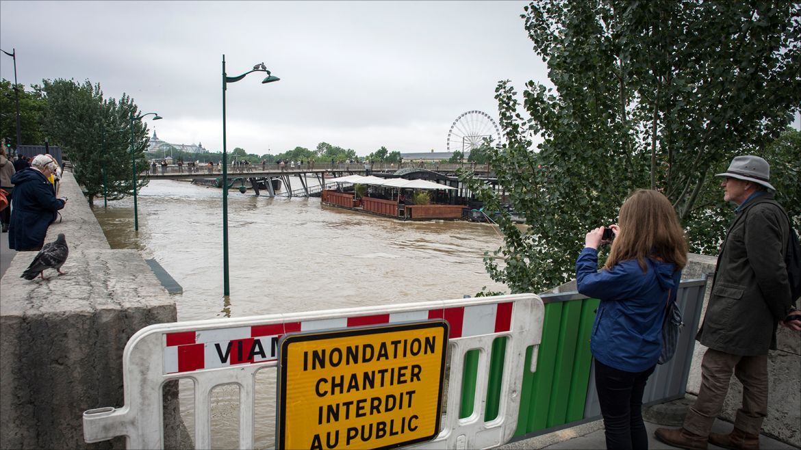 epa05343899 Pedestrians stand near a sign reading 'Floods Work Zone Forbidden to Public', along the Seine river in Paris, France, 03 June 2016. Floods and heavy rain drenched about a quarter of the French territory over several days.  EPA/JEREMY LEMPIN