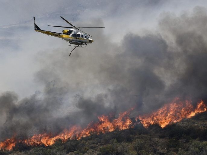A fire fighting aircraft releases water as firefighters battle the thousand-acre plus 'Fish' wildland fire that erupted near the Angeles National Forest, Duarte, Califonia, USA, 20 June 2016. High temperatures over 100 degrees Fahrenheit (38 degrees Celsius) have hampered firefighting efforts throughout Southern California.