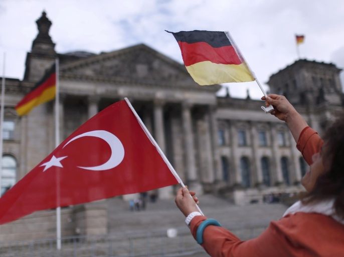 A demonstrator holds Turkish and German flags in front of the Reichstag, the seat of the lower house of parliament Bundestag in Berlin, Germany, June 1, 2016, as she protests against a disputed vote in Germany's parliament on Thursday, on a resolution that labels the killings of up to 1.5 million Armenians by Ottoman forces as genocide. REUTERS/Hannibal Hanschke