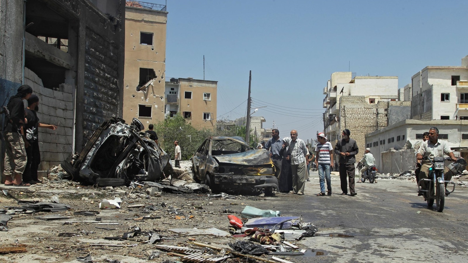 ‪سيارتان مدمرتان جراء غارة جوية شنت اليوم على مدينة إدلب غربي سوريا‬ (رويترز)