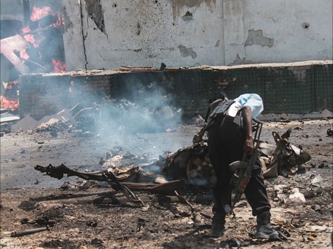 epa05449637 A man checks the remains of a destroyed car at the scene of a sucide attack in Mogadishu, Somalia, 31 July 2016. Explosions and gunfire were heard after attackers drove a car bomb into the Criminal Investigation Department (CID) headquarters in the capital Mogadishu, according to reports. The number of casualties are unknown. The country's Islamist militant group al-Shabab has claimed the responsibility for the latest attack. EPA/SAID YUSUF WARSAME