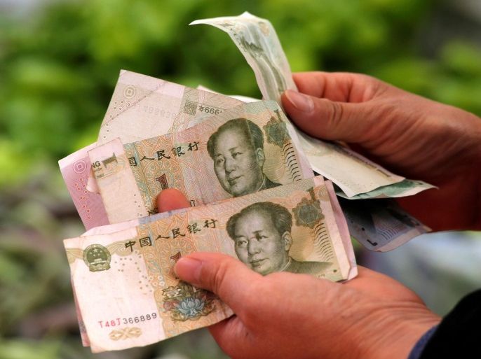 A customer counts Chinese Yuan banknotes as she purchases vegetables at a market in Beijing, China, May 9, 2016. REUTERS/Kim Kyung-Hoon/File Photo