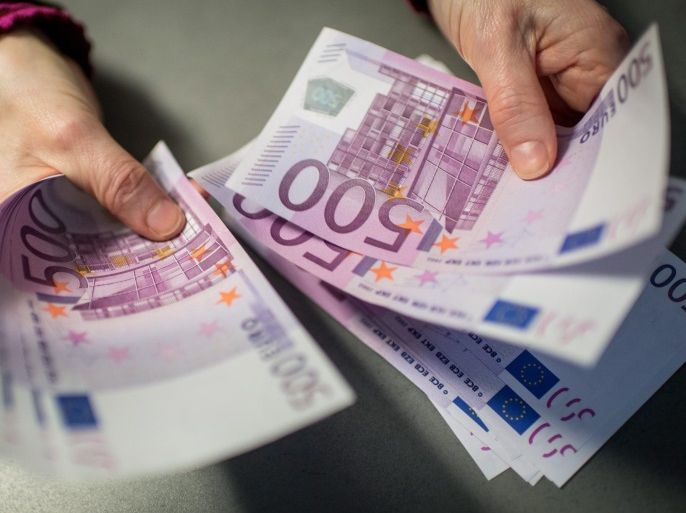 A bank employee holds 5,000 euros in 500-euro notes at a Sparkasse bank in Munich, Germany, 3 February 2016. Germany is considering imposing an upper limit on payments in cash as part of its fight against terrorism and money laundering.
