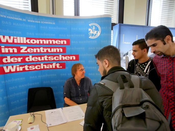 Unidentified youths look at the stand of the Schwerin Chamber of Trade at the first job training fair for refugees at the Chamber of Industry and Commerce in Schwerin, Germany, 14 July 2016. Slogan on background wall reads: 'Welcome to the Center of the German Economy'. More than 300 young people, many of them from Syria and Eritrea, visited the trade fair.