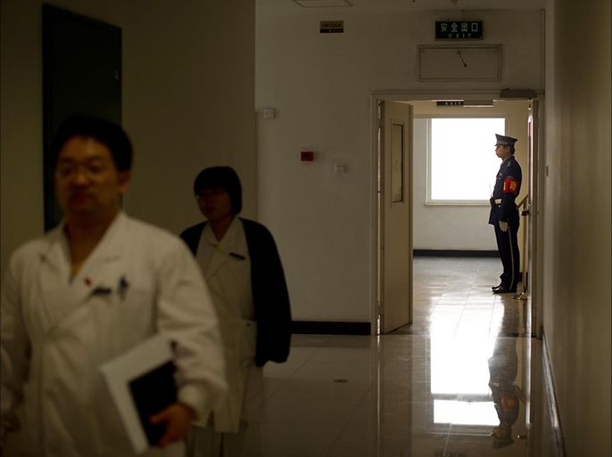 مرور طبيب صيني بينما يظهر حارس أمن على باب أحد الممرات في مستشفى بكين المركزي