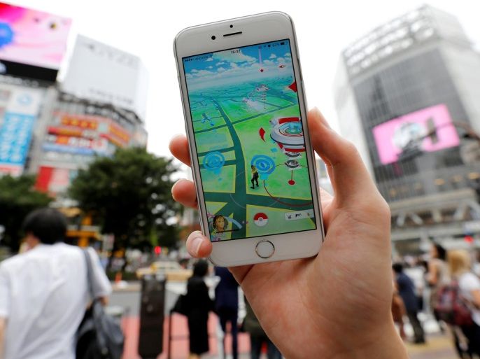 A man poses with his mobile phone displaying the augmented reality mobile game "Pokemon Go" by Nintendo in front of a busy crossing in Shibuya district in Tokyo, Japan, July 22, 2016. REUTERS/Toru Hanai
