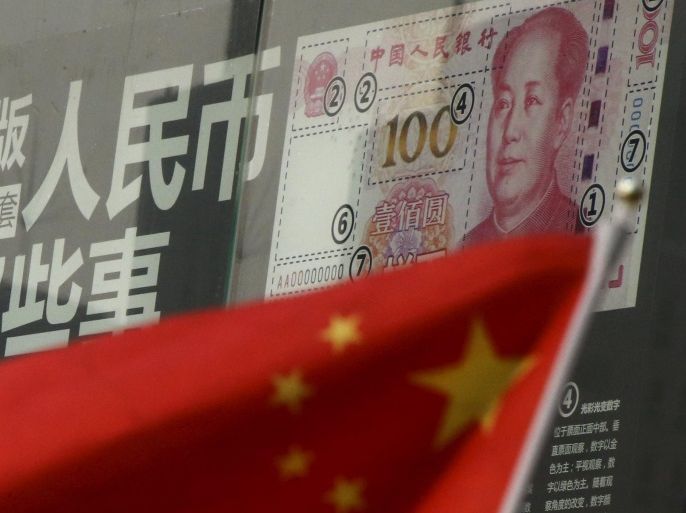 China's national flag is seen in front of a poster explaining the design of new 100 yuan banknote at a branch of a commercial bank at a business district in Beijing, China, in this January 21, 2016 file picture. China plans to target broad-based money supply growth of around 13 percent this year, sources said, a signal that further monetary policy easing is likely during a painful economic restructuring that could see millions of workers losing jobs. REUTERS/Kim Kyung-