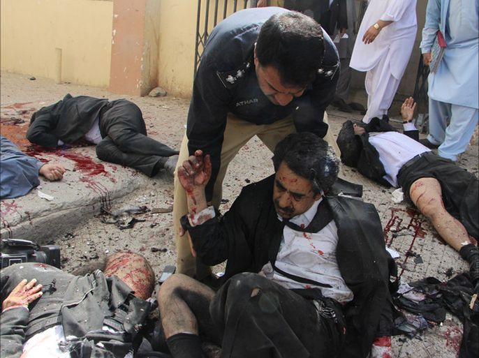epa05464058 A police officer helps an injured lawyer after a bomb explosion in restive Quetta, Pakistan, 08 August 2016.