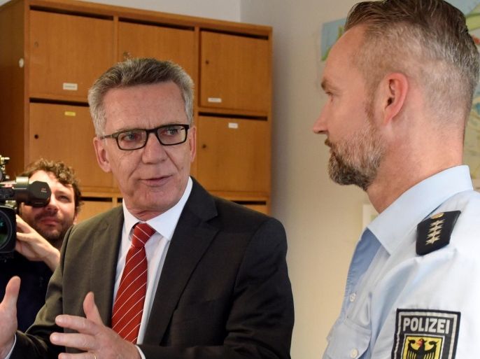 German Interior Minister Thomas de Maiziere speaks with police officer Ralf Bruns during his visit at the federal police inspection in Bremen, Germany, August 10, 2016.REUTERS/Fabian Bimmer