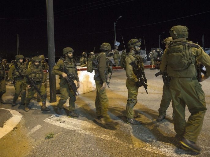 Israeli soldiers stand at scene of a shooting attack on an Israeli army checkpoint near the West Bank town of Beitunia, on route 443, west of Ramallah, late 11 March 2016. Israeli army report that during a routine security check a Palestinian gunman opened fire and wounded moderately two Israel soldiers, forces are conducting extensive searches in the area for the gunman who fled the scene.