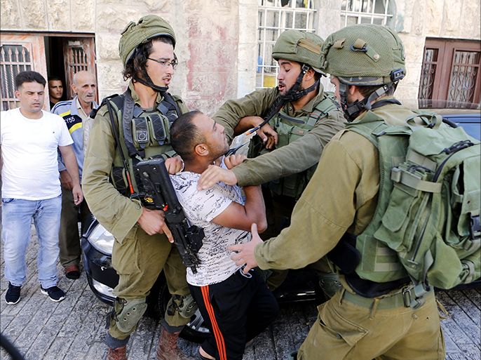 epa05549469 Israeli army soldiers restrain a Palestinian as he is being arrested following scuffling during raids on houses in the West Bank city of Hebron, 20 September 2016. Clashes in Hebron broke out after the most recent case of a Palestinian assailant being killed by the Israeli army on 20 September 2016. EPA/ABED AL HASHLAMOUN