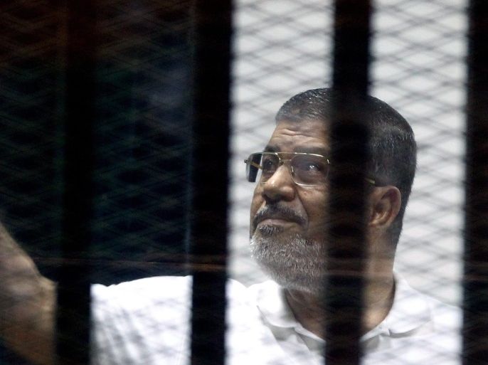 Ousted Egyptian president Mohamed Morsi stands behind dock bars during a trial session, in Cairo, Egypt, 13 July 2014. Ousted president Mohamed Morsi and some 130 defendants from the Muslim Brotherhood face a trial on charges of allegedly escaping from prison back in 2011 during the early days of the uprising.
